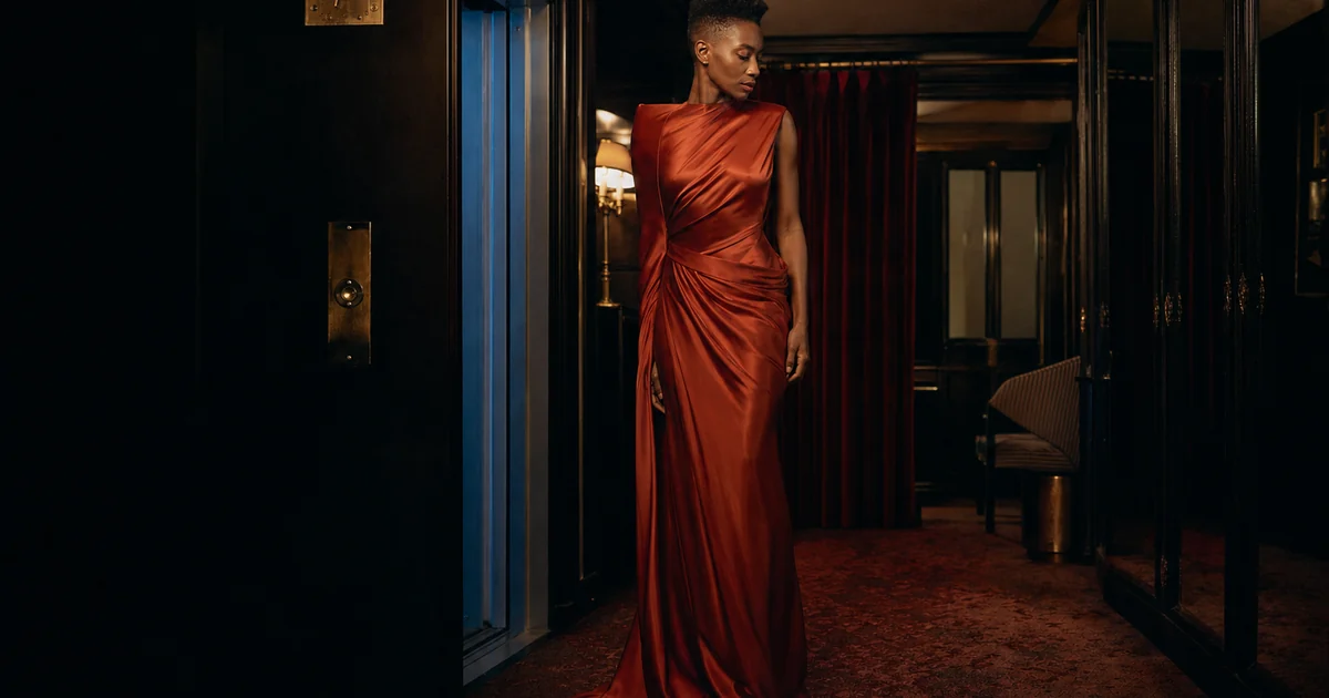 Hotel 00:07 fashion concept, a woman in a copper dress at a hotel doorway